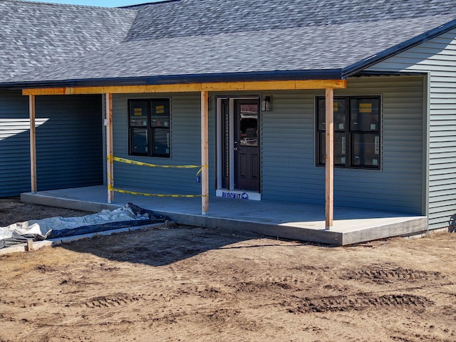 property entrance featuring a shingled roof and covered porch