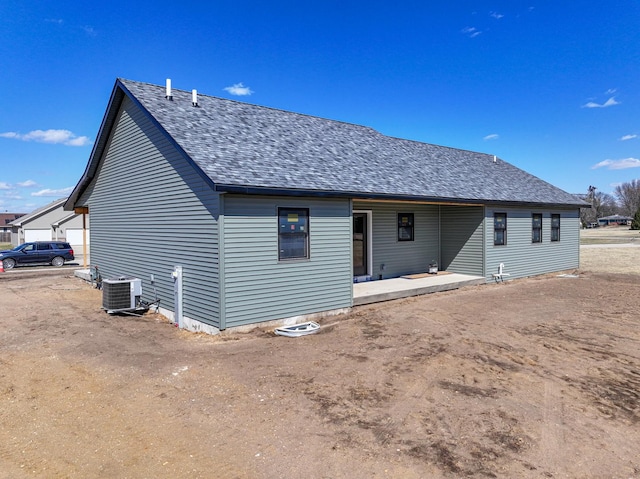 rear view of property with a shingled roof and central air condition unit