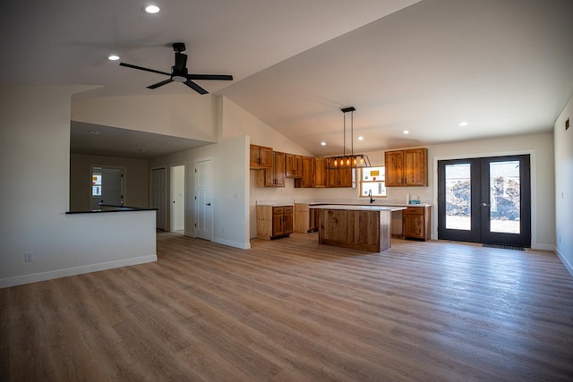 kitchen featuring a center island, open floor plan, brown cabinets, and baseboards