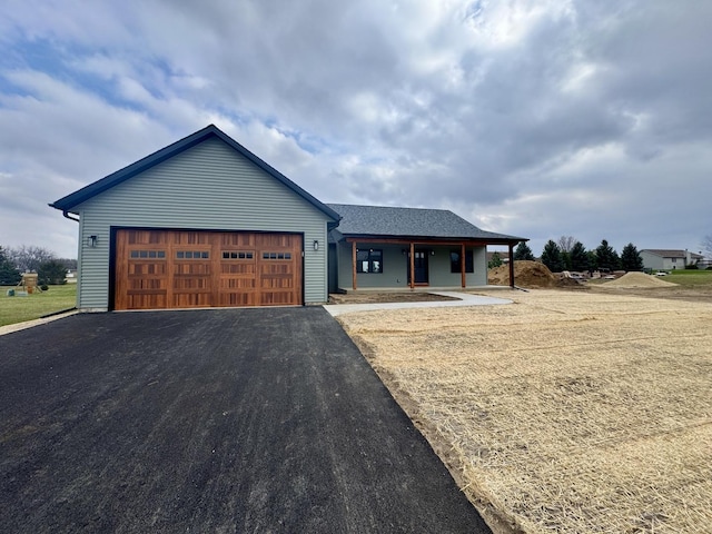ranch-style house with a porch, an attached garage, and aphalt driveway