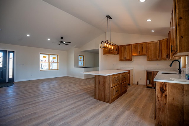 kitchen featuring light wood-type flooring, vaulted ceiling, recessed lighting, brown cabinets, and a sink