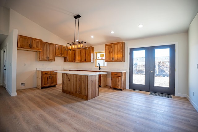 kitchen with light wood-style flooring, french doors, lofted ceiling, brown cabinets, and a kitchen island