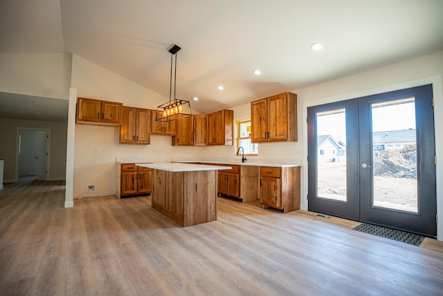 kitchen with french doors, a sink, light wood-type flooring, brown cabinets, and a kitchen island