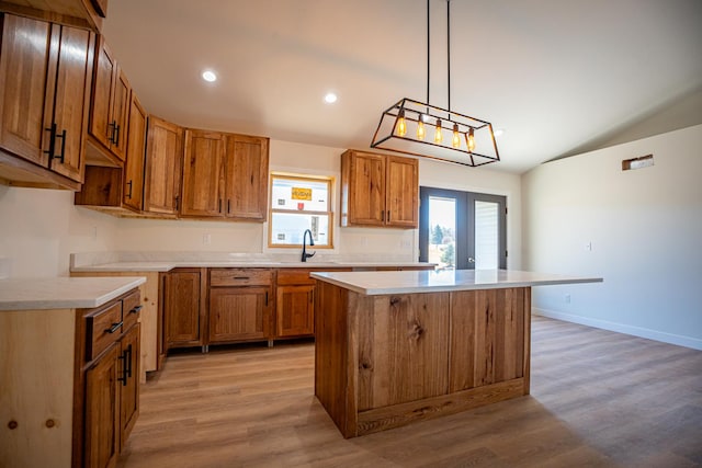 kitchen featuring light wood-type flooring, vaulted ceiling, brown cabinets, light countertops, and a kitchen island