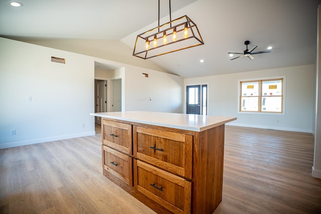 kitchen with brown cabinetry, vaulted ceiling, open floor plan, and light wood finished floors