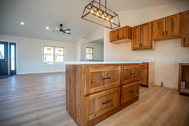 kitchen featuring light wood-type flooring, vaulted ceiling, brown cabinets, and ceiling fan