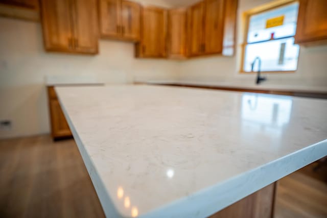 kitchen with brown cabinets, a center island, wood finished floors, and light countertops