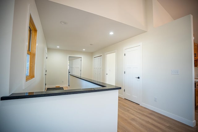 kitchen featuring dark countertops, light wood-style floors, baseboards, a peninsula, and recessed lighting