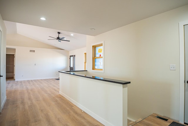 kitchen with dark countertops, light wood-type flooring, ceiling fan, lofted ceiling, and visible vents