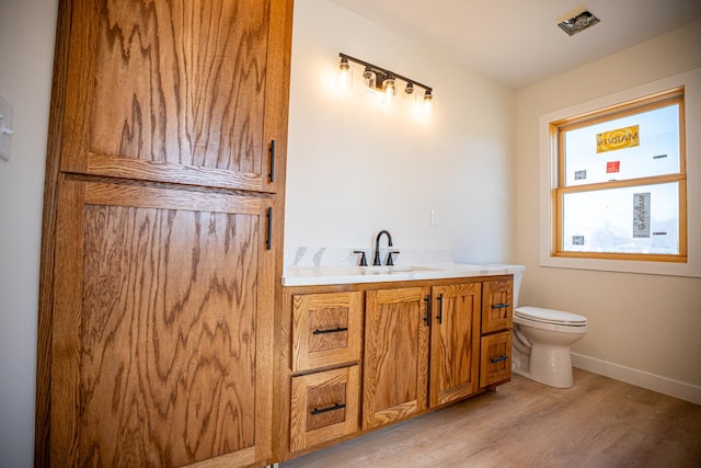 bathroom featuring baseboards, wood finished floors, vanity, and toilet