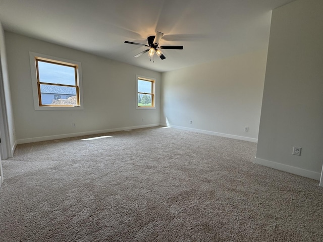 carpeted spare room with a ceiling fan and baseboards
