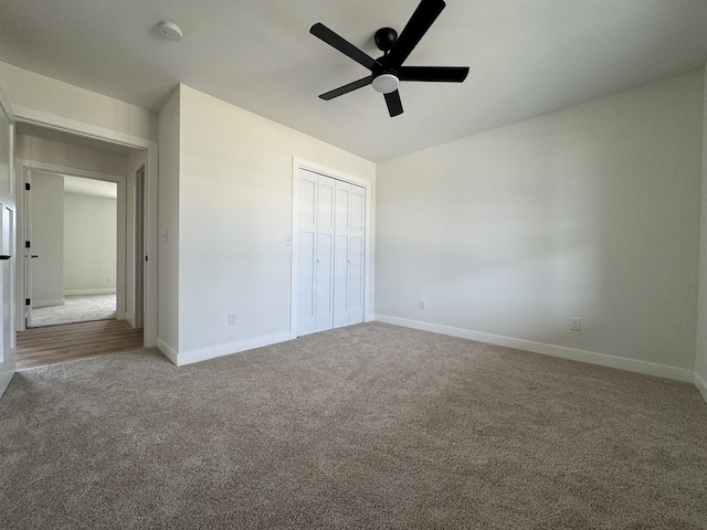 unfurnished bedroom with ceiling fan, baseboards, carpet flooring, and a closet