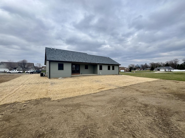view of front of house with a shingled roof and dirt driveway