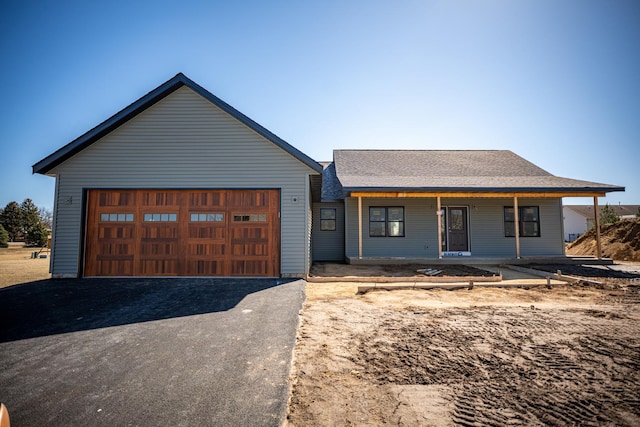 view of front of property featuring a garage, aphalt driveway, roof with shingles, and covered porch