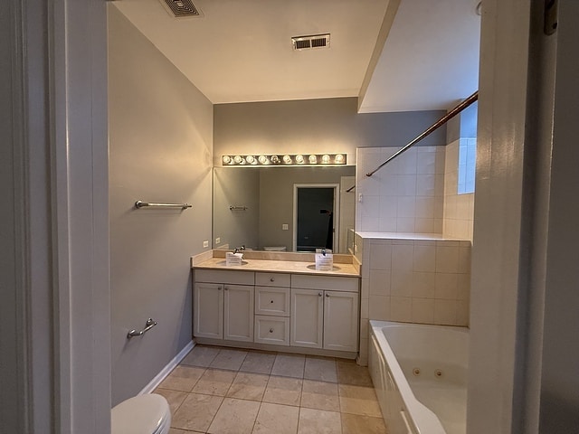 full bathroom featuring vanity, toilet, tiled shower / bath combo, and tile patterned flooring