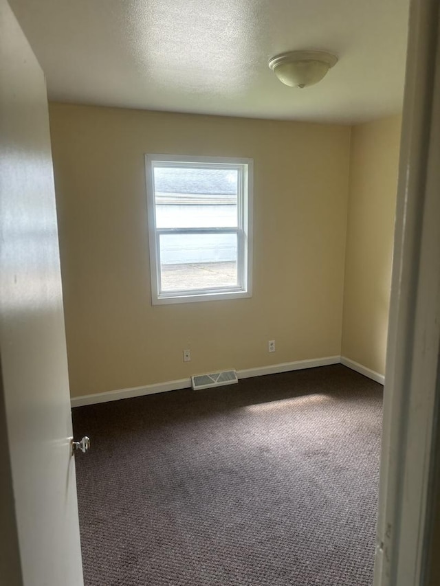 carpeted empty room featuring a textured ceiling