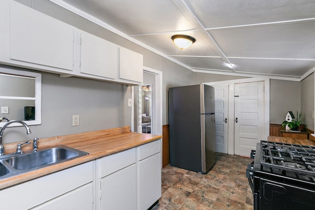 kitchen featuring vaulted ceiling, stainless steel refrigerator, white cabinetry, sink, and black gas stove