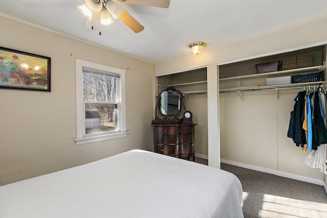 bedroom with crown molding, two closets, ceiling fan, and carpet flooring