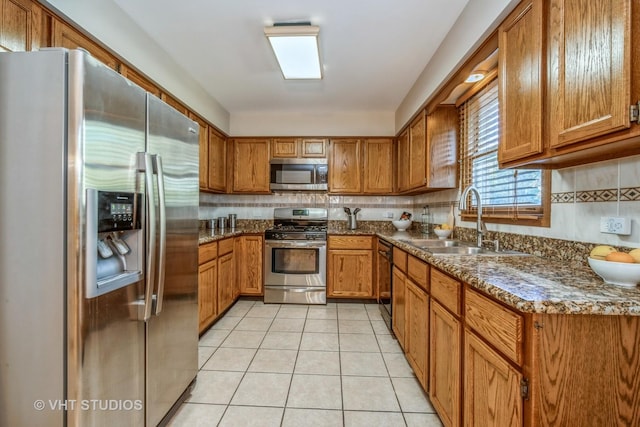 kitchen with light tile patterned flooring, appliances with stainless steel finishes, sink, and dark stone countertops