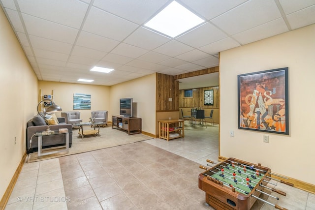 tiled living room featuring wooden walls and a drop ceiling