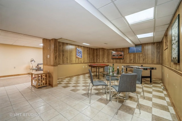 dining room featuring a paneled ceiling and wooden walls