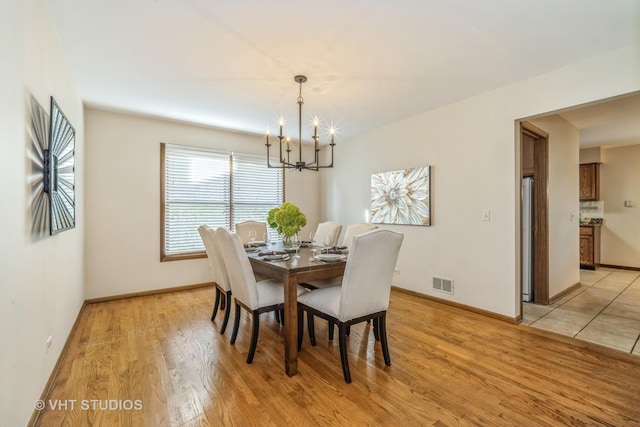 dining area with a notable chandelier and light hardwood / wood-style floors