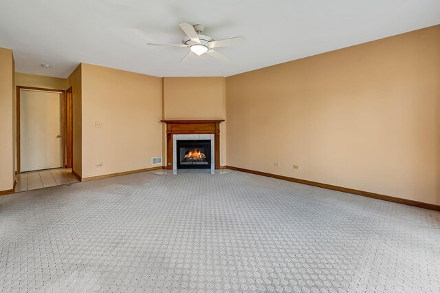 unfurnished living room with light colored carpet, ceiling fan, visible vents, baseboards, and a tile fireplace