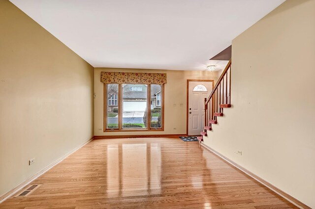 foyer entrance with stairway, visible vents, light wood finished floors, and baseboards
