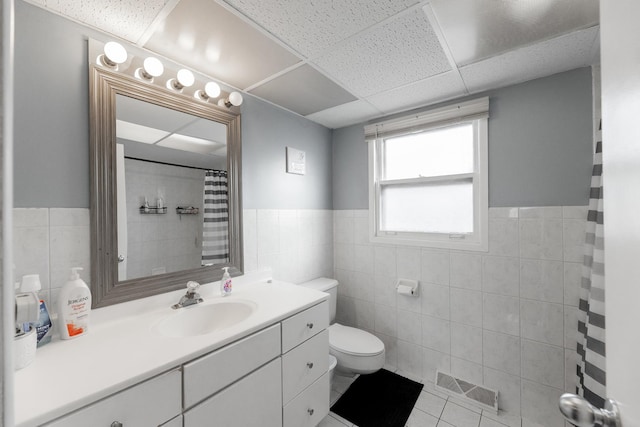 bathroom with vanity, tile patterned flooring, tile walls, and toilet