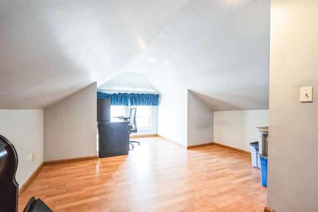 additional living space featuring vaulted ceiling and light wood-type flooring