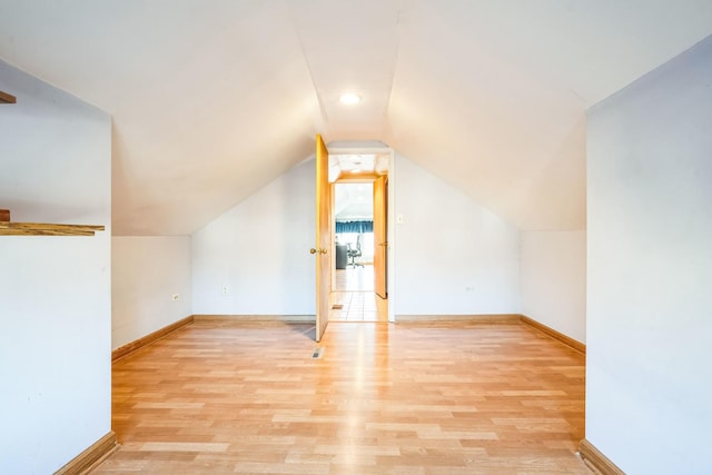 additional living space featuring lofted ceiling and light hardwood / wood-style floors