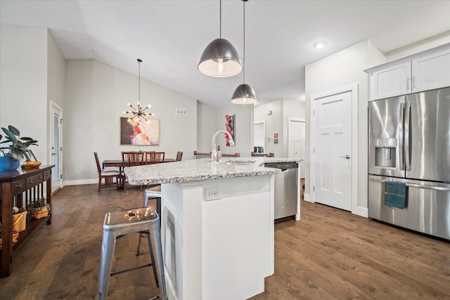 kitchen with pendant lighting, sink, white cabinets, stainless steel appliances, and a center island with sink