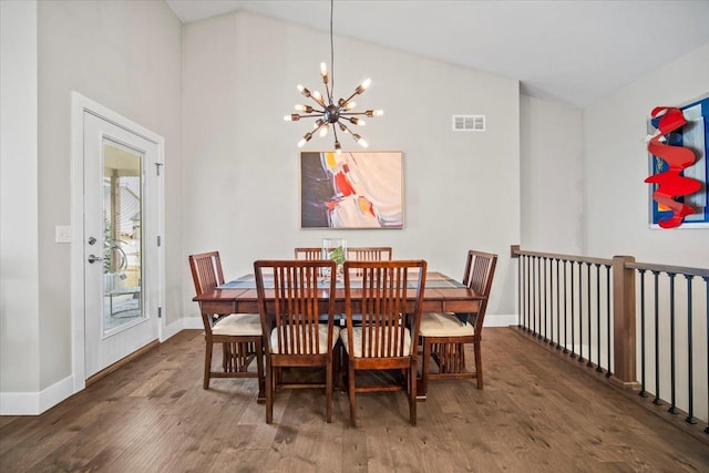 dining room featuring lofted ceiling, dark hardwood / wood-style floors, and a chandelier