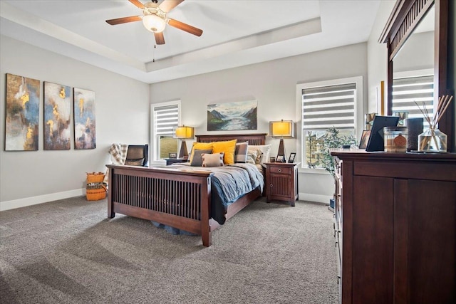 bedroom with light carpet, ceiling fan, and a tray ceiling