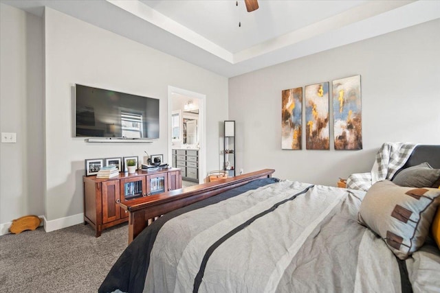 carpeted bedroom featuring a raised ceiling, ensuite bathroom, and ceiling fan