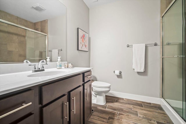 bathroom with vanity, a shower with door, and toilet