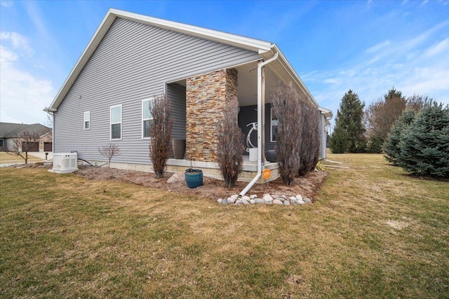 rear view of property with central AC unit and a lawn