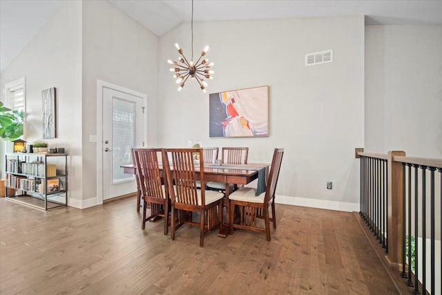 dining area featuring high vaulted ceiling, hardwood / wood-style floors, and a chandelier