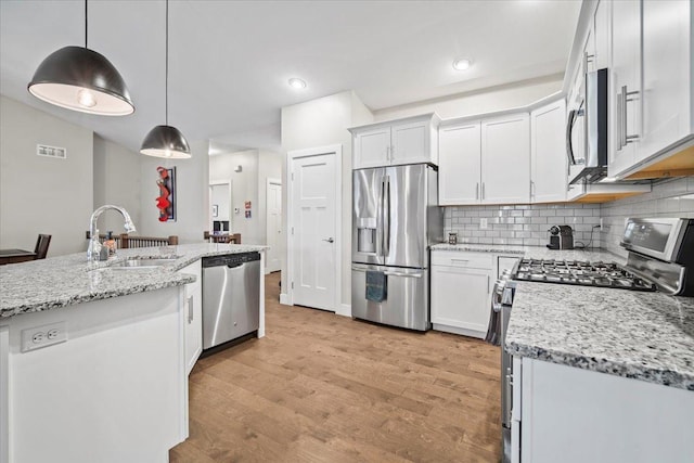 kitchen with appliances with stainless steel finishes, sink, pendant lighting, and white cabinets