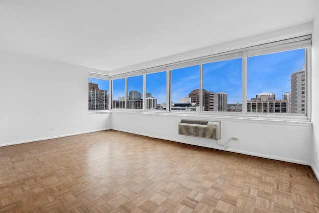 empty room featuring an AC wall unit and light parquet flooring