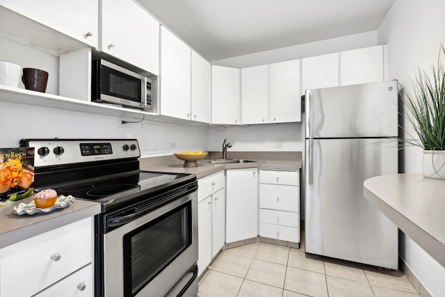 kitchen featuring white cabinetry, sink, light tile patterned floors, and stainless steel appliances