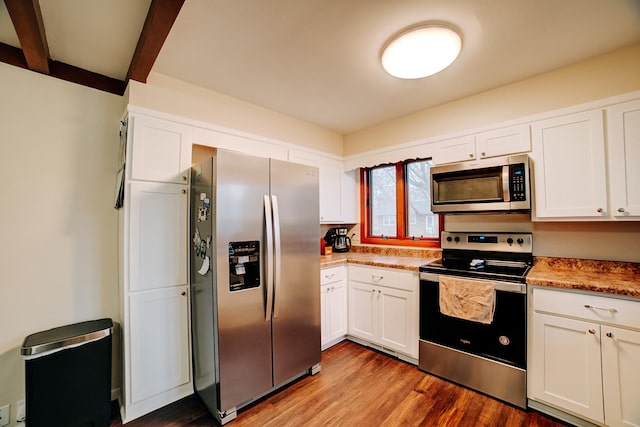 kitchen featuring hardwood / wood-style flooring, beam ceiling, stainless steel appliances, light stone countertops, and white cabinets