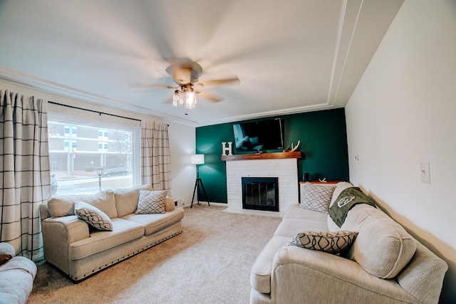 living room with a fireplace, ornamental molding, ceiling fan, and carpet