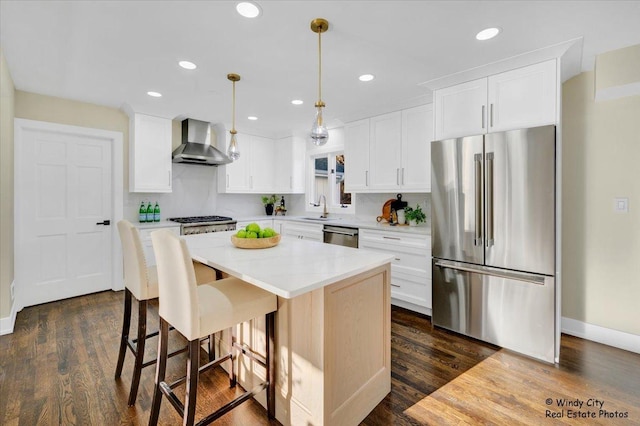 kitchen featuring white cabinetry, stainless steel appliances, a center island, and wall chimney exhaust hood