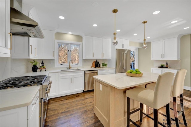 kitchen with wall chimney range hood, white cabinetry, hanging light fixtures, a center island, and premium appliances