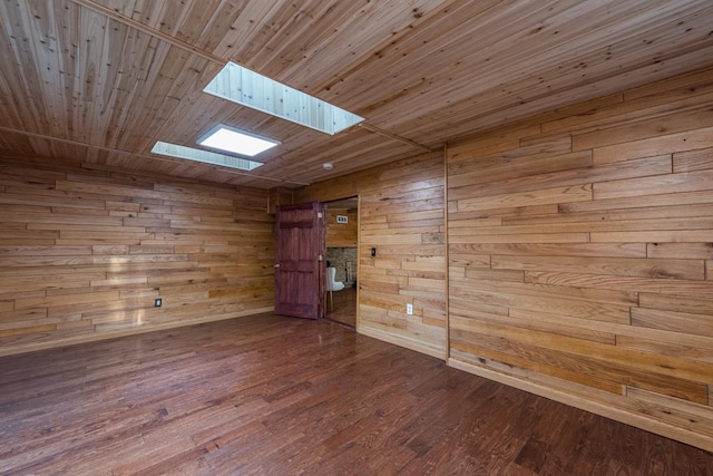 empty room featuring hardwood / wood-style flooring, wooden ceiling, a skylight, and wood walls