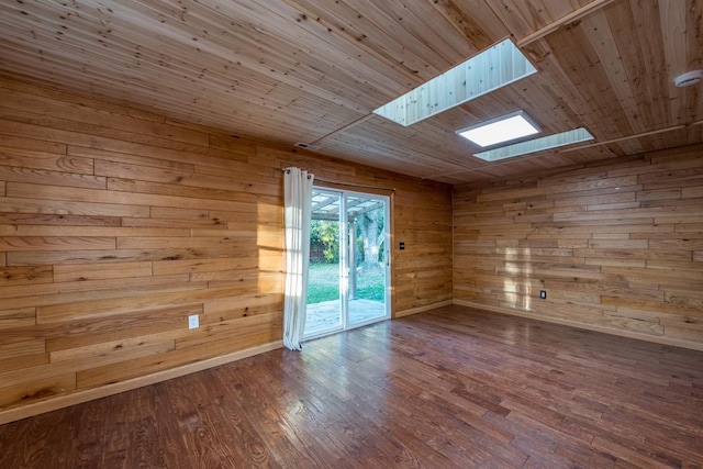 empty room featuring hardwood / wood-style floors, wood ceiling, a skylight, and wooden walls