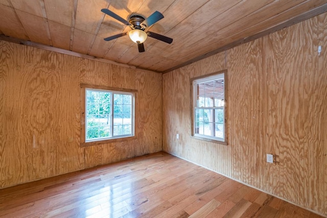 empty room featuring ceiling fan, wood walls, light hardwood / wood-style flooring, and wooden ceiling