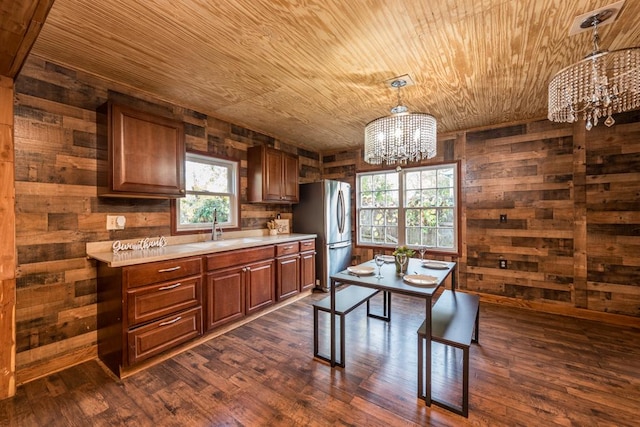 kitchen featuring sink, an inviting chandelier, wooden ceiling, stainless steel fridge, and wooden walls