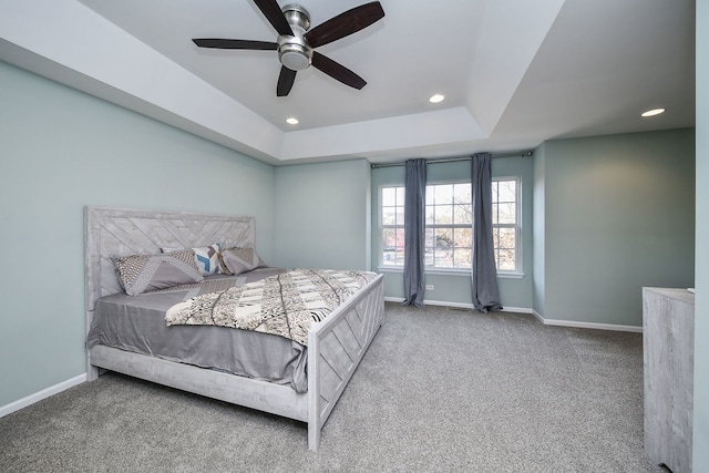 bedroom with a raised ceiling, ceiling fan, and carpet flooring